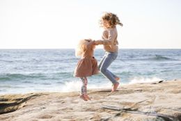 Sisters jumping and laughing on the rocks